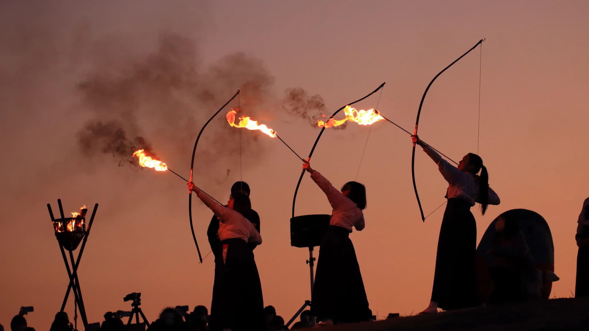 Archers loose flaming arrows at dusk during the Fire Festival at Cape Shionomisaki, Wakayama