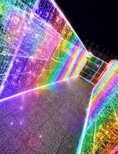 A narrow passage between walls of lights in rainbow colours