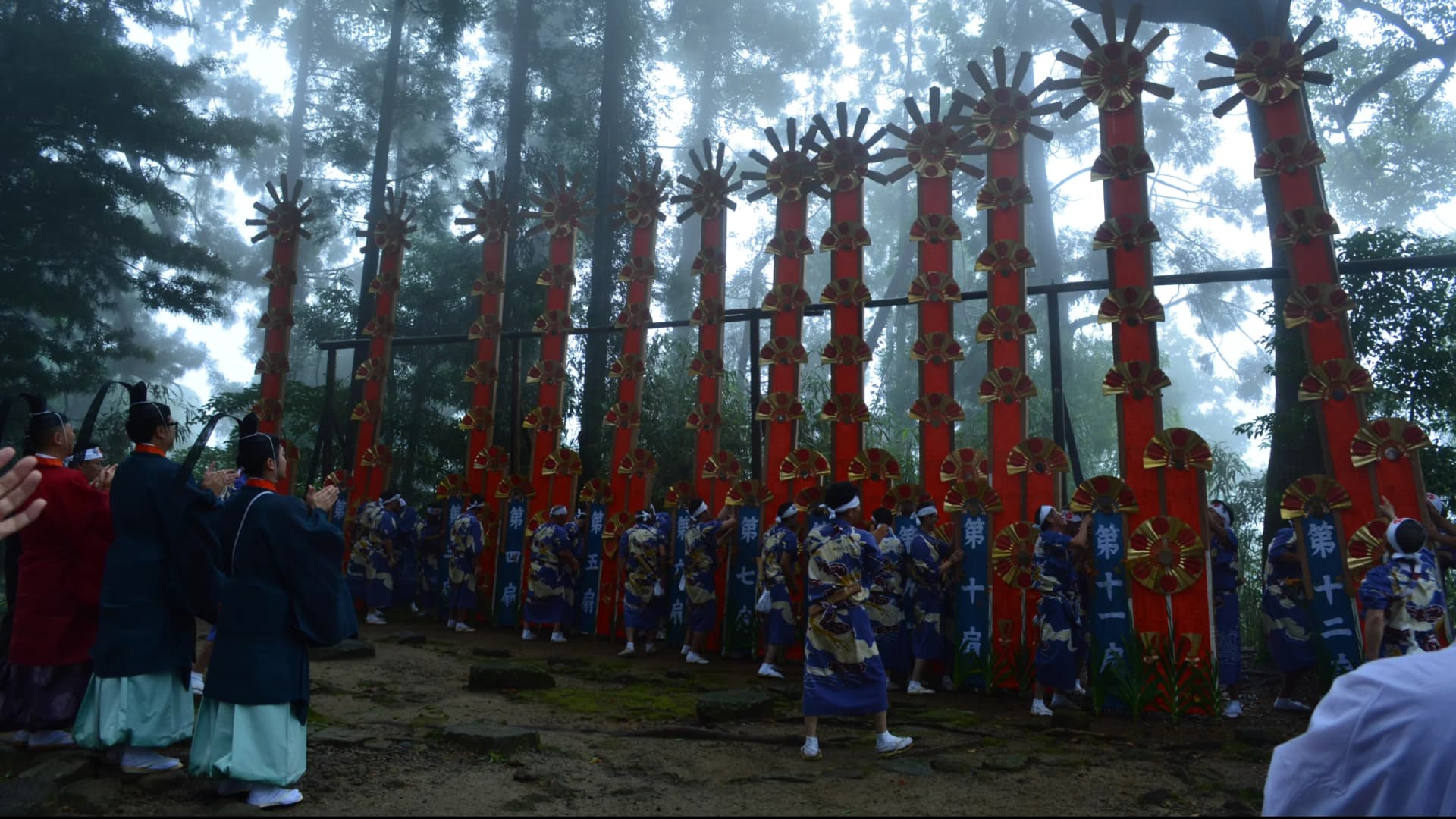 The towering "ogi mikoshi" fan-decorated portable shrines stand in the misty forest at the Nachi Fire Festival, Wakayama