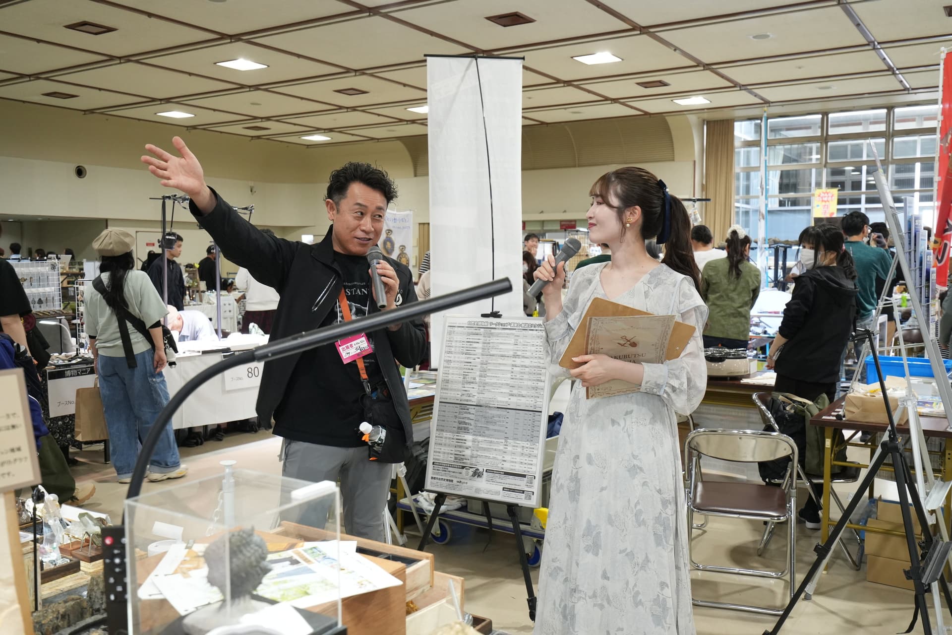 Two presenters with microphones introducing exhibits on the floor at a previous Hakubutsu Mania