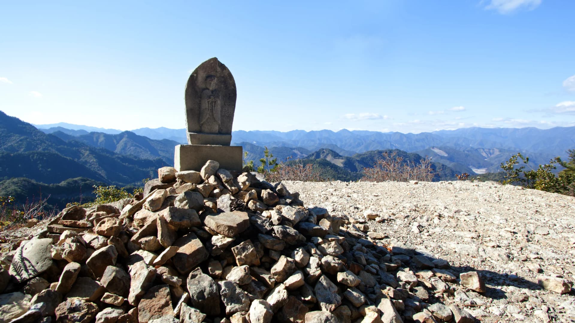 A weathered stone Buddha atop a cairn overlooks the Kumano mountains along the Nakahechi route, Wakayama