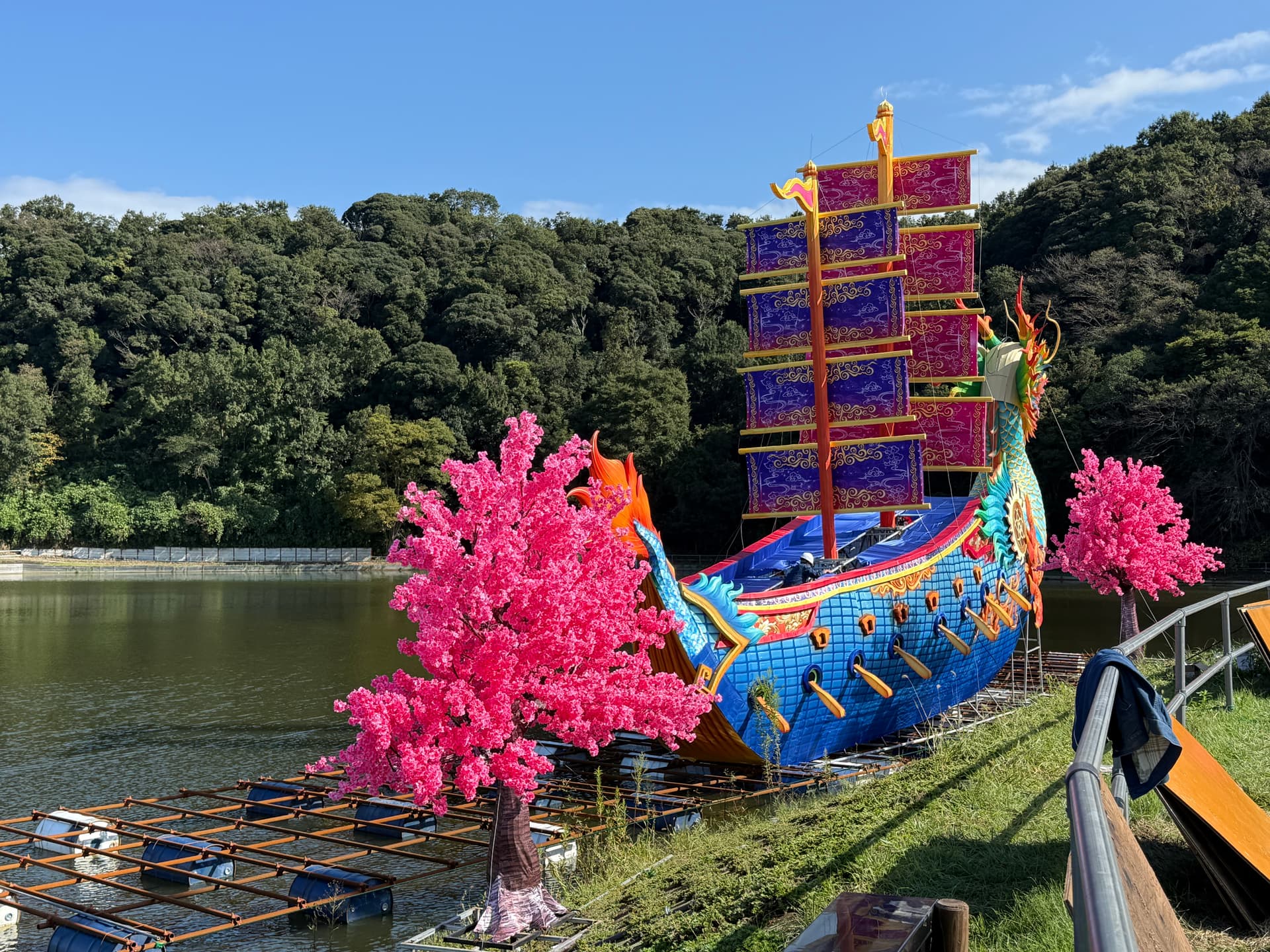 The dragon ship lantern being built on the lake at Tokyo German Village in 2026, with two artificial cherry trees on the shore